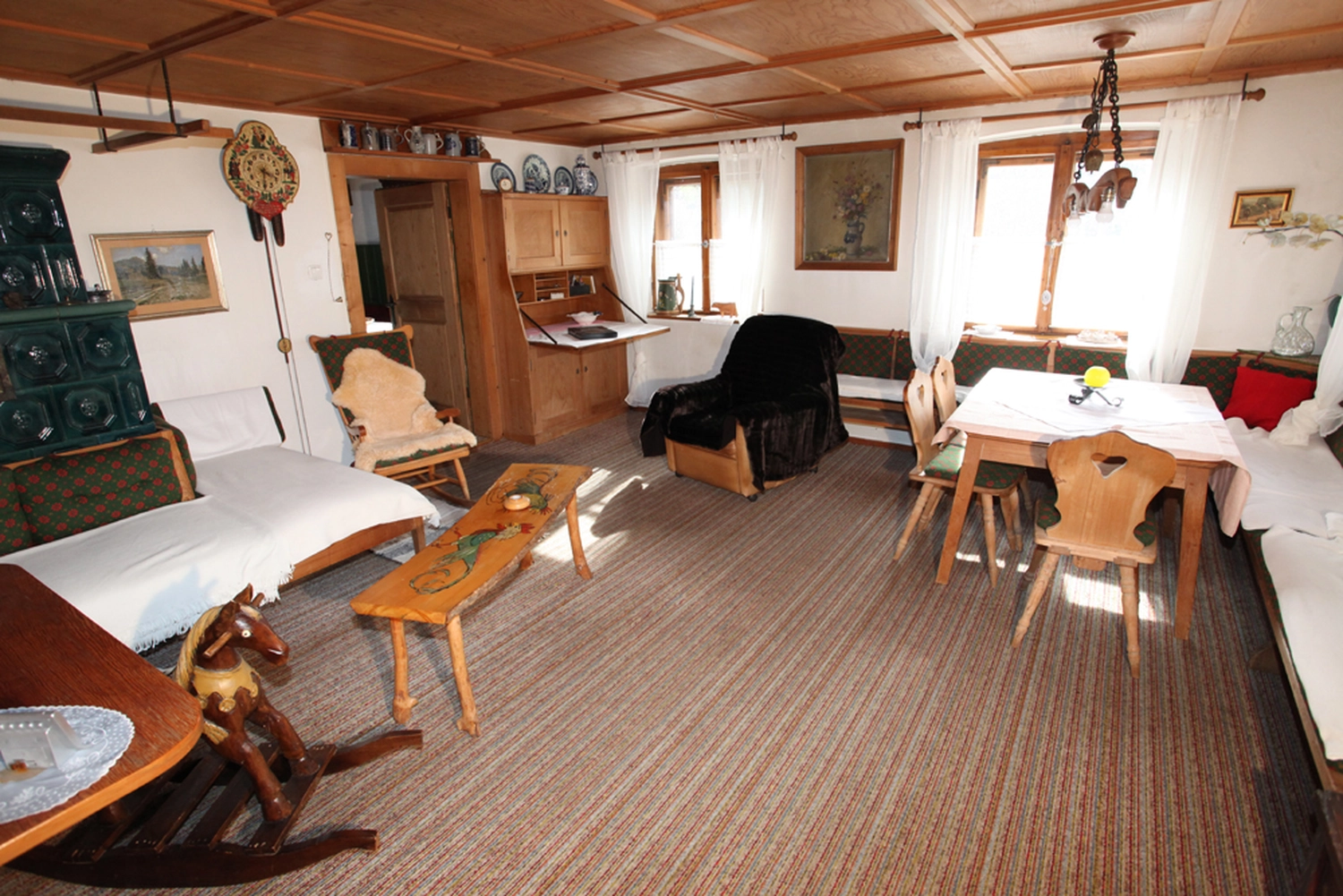 Antjes – Roomstyling –  Vorher: Ein gemütliches Wohn- und Esszimmer im Landhausstil mit braunem Teppich, Holzmöbeln und einer Holzbalkendecke.